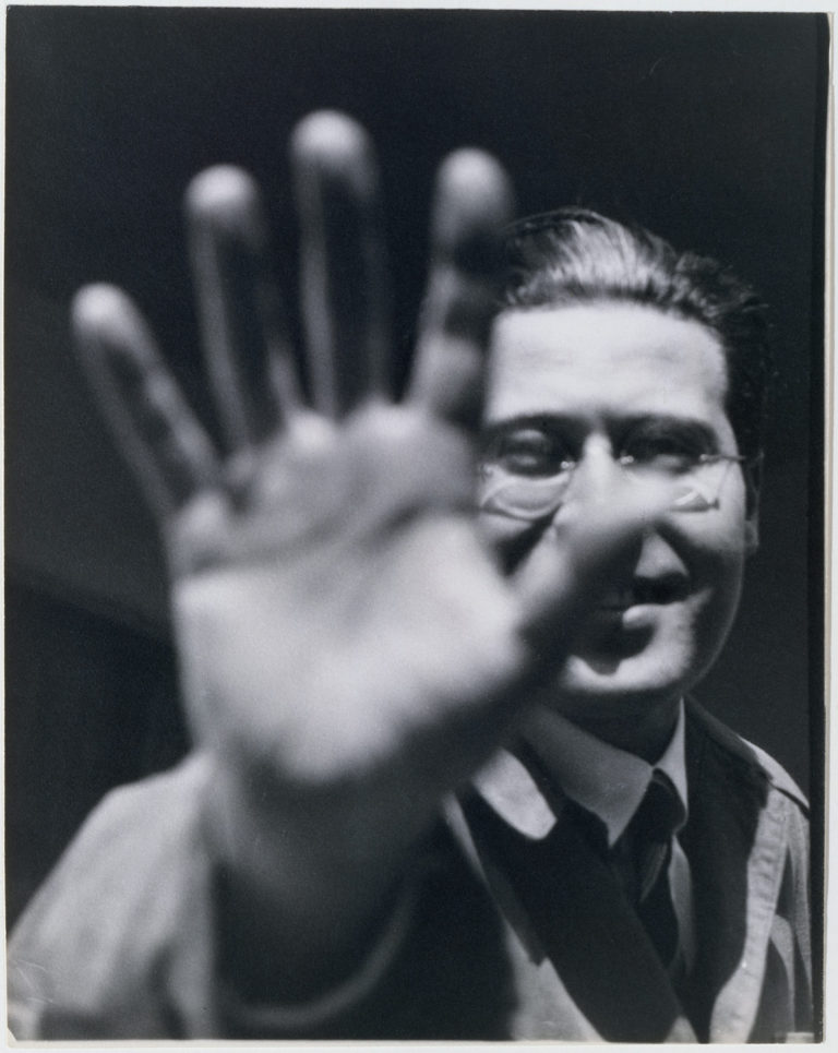 Retrato de Lászlo Moholy-Nagy realizado por Lucia Schulz, enfocado el segundo plano y desenfocada la mano que aparece en el primero.